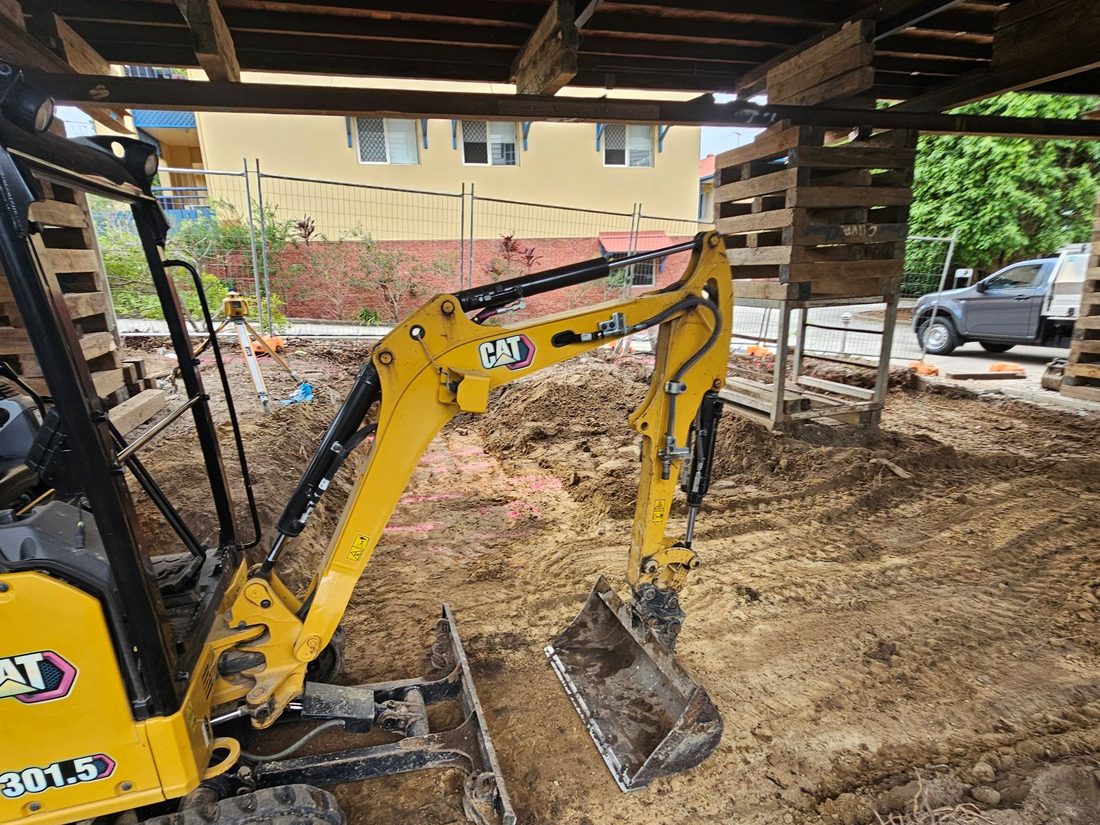 Excavator working beneath a raised Queenslander